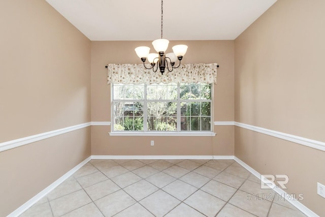 unfurnished room featuring a notable chandelier and baseboards