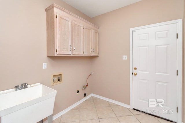 washroom with light tile patterned floors, a sink, cabinet space, washer hookup, and baseboards