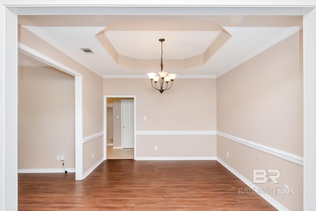 unfurnished room featuring wood finished floors, visible vents, a chandelier, a tray ceiling, and baseboards