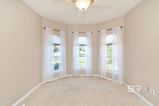 carpeted spare room featuring ceiling fan and baseboards