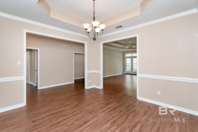 spare room featuring a notable chandelier, baseboards, visible vents, wood finished floors, and a raised ceiling