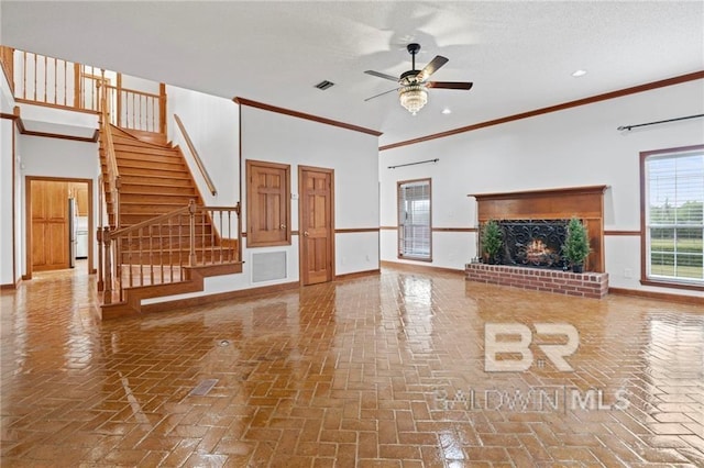 unfurnished living room featuring crown molding, ceiling fan, a textured ceiling, and a brick fireplace