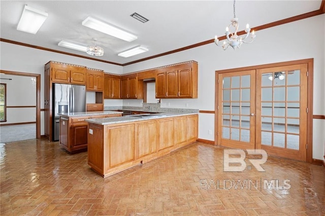 kitchen with a notable chandelier, kitchen peninsula, crown molding, pendant lighting, and a kitchen island