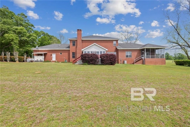 rear view of house featuring a yard, a garage, and a sunroom