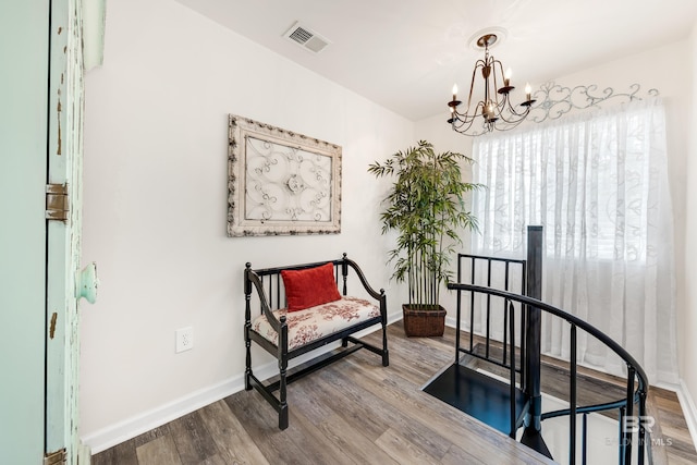 sitting room with hardwood / wood-style flooring and an inviting chandelier