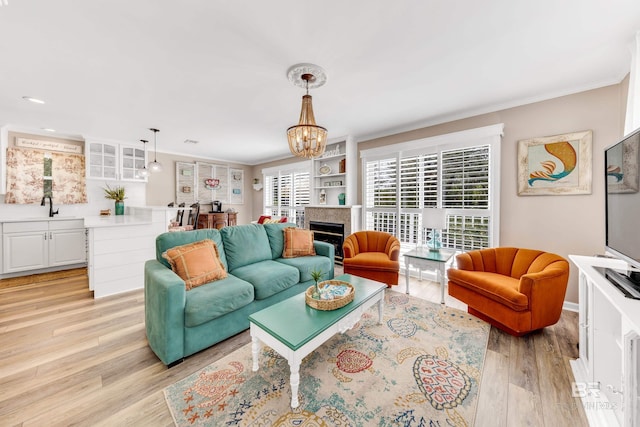 living room featuring light wood-type flooring, crown molding, a wealth of natural light, and a chandelier