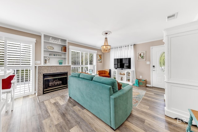 living room featuring wood-type flooring, ornamental molding, and an inviting chandelier