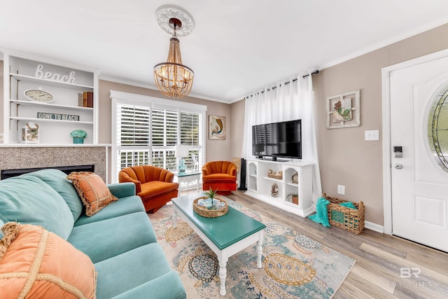 living room with a chandelier, light hardwood / wood-style floors, and ornamental molding