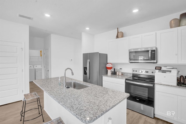 13729 Shea Cir, Foley, AL 36535 - kitchen with appliances with stainless steel finishes, a sink, washing machine and dryer, light wood-style flooring, and recessed lighting