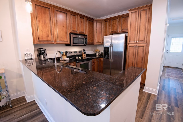 kitchen featuring stainless steel appliances, dark stone countertops, kitchen peninsula, and dark wood-type flooring