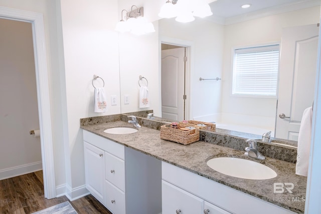 bathroom with ornamental molding, hardwood / wood-style floors, vanity, and a bathtub