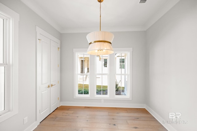 unfurnished dining area with a healthy amount of sunlight, light wood-type flooring, and ornamental molding