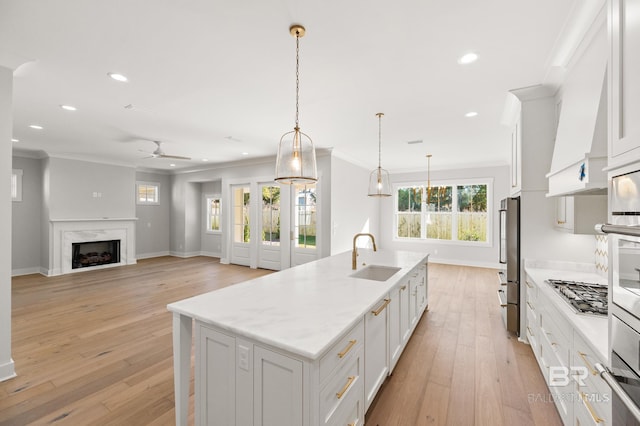 kitchen with pendant lighting, white cabinets, sink, an island with sink, and appliances with stainless steel finishes