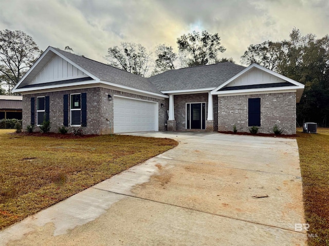 view of front of home with a garage, a lawn, and cooling unit