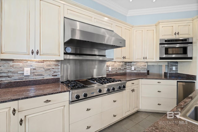 kitchen with cream cabinets, dark stone counters, and appliances with stainless steel finishes