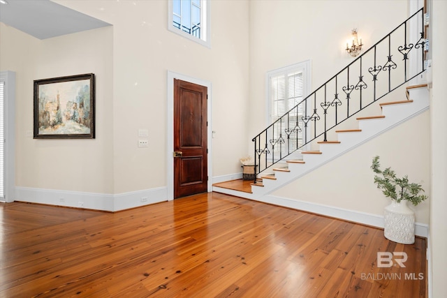 foyer entrance with hardwood / wood-style floors and a towering ceiling