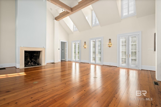 unfurnished living room featuring beamed ceiling, high vaulted ceiling, and light hardwood / wood-style floors