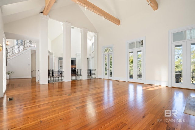 interior space with beam ceiling, french doors, high vaulted ceiling, and hardwood / wood-style flooring