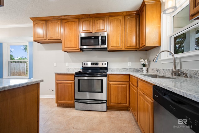 kitchen with light stone counters, a textured ceiling, appliances with stainless steel finishes, and sink