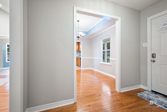 foyer with ornamental molding, a notable chandelier, and light hardwood / wood-style floors