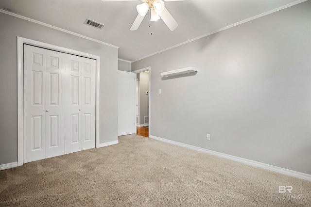 unfurnished bedroom with carpet floors, crown molding, ceiling fan, and a closet