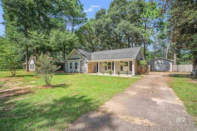 view of front of home featuring an outdoor structure, a garage, covered porch, and a front yard