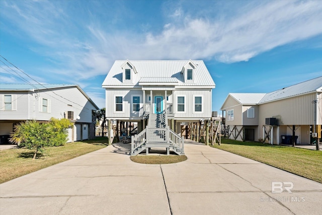 raised beach house featuring a front lawn, a garage, and covered porch