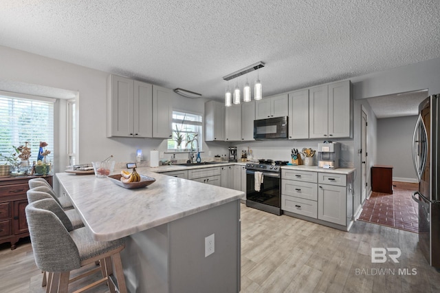 kitchen with kitchen peninsula, range with electric cooktop, gray cabinets, and hanging light fixtures