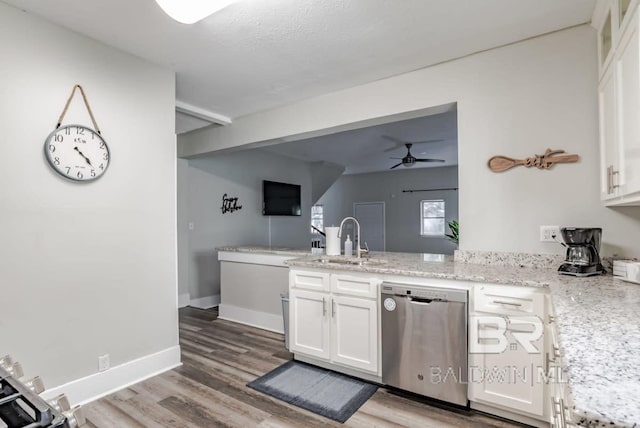 kitchen with a sink, stainless steel dishwasher, wood finished floors, a peninsula, and white cabinets