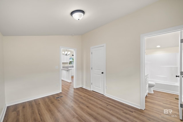 1096 S Pine St, Loxley, AL 36551 - unfurnished bedroom featuring wood finished floors, a chandelier, vaulted ceiling, and ensuite bath