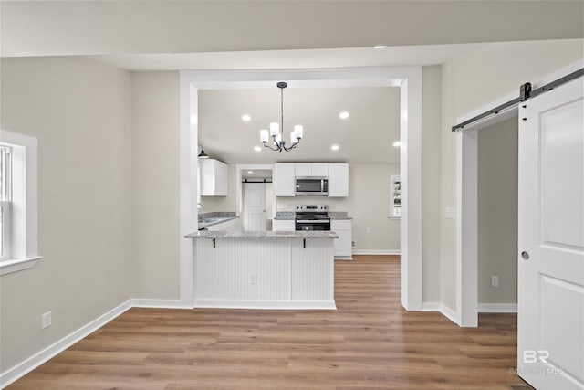 1096 S Pine St, Loxley, AL 36551 - kitchen featuring appliances with stainless steel finishes, a barn door, white cabinetry, light wood-type flooring, and recessed lighting