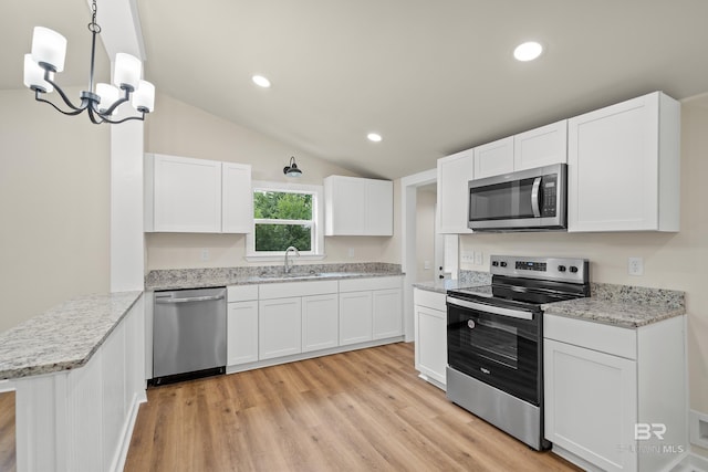 1096 S Pine St, Loxley, AL 36551 - kitchen with stainless steel appliances, light wood-style flooring, white cabinetry, vaulted ceiling, and a peninsula