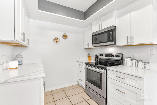 kitchen with stainless steel appliances, white cabinetry, light stone countertops, and light tile patterned floors