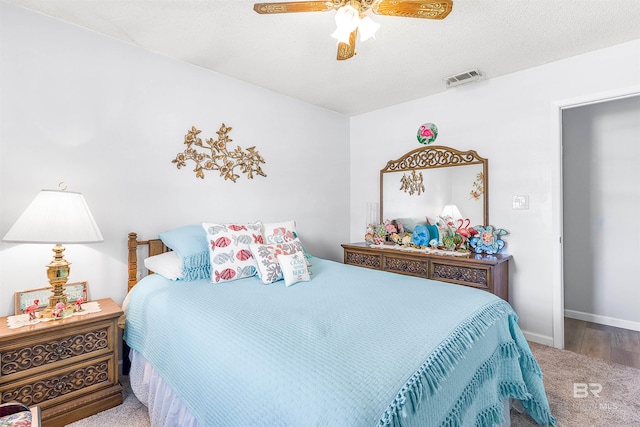 carpeted bedroom featuring ceiling fan and a textured ceiling