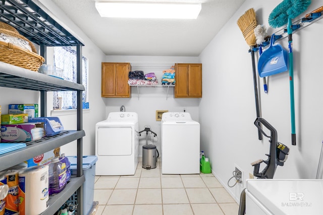 laundry area with cabinets, washing machine and clothes dryer, and light tile patterned floors