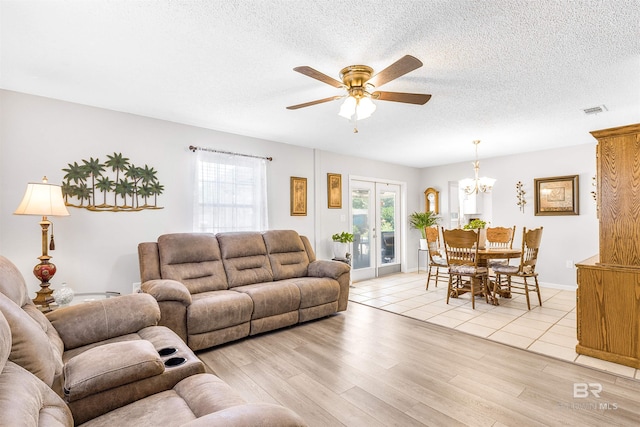 living room with ceiling fan with notable chandelier, light hardwood / wood-style floors, french doors, and a textured ceiling