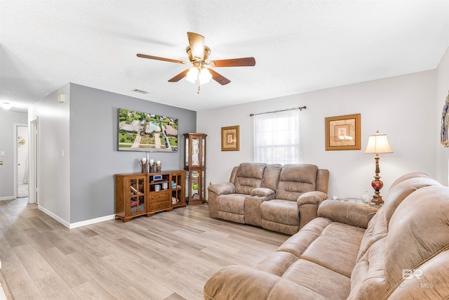 living room with ceiling fan, a textured ceiling, and light hardwood / wood-style flooring