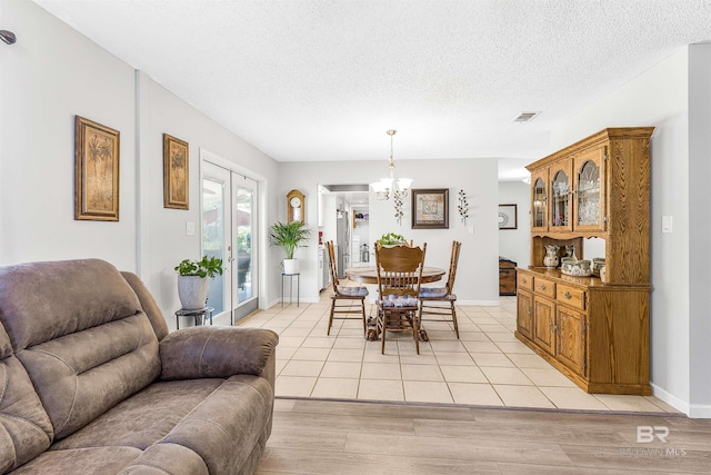 dining room featuring a notable chandelier, a textured ceiling, and light wood-type flooring