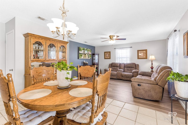 tiled dining space with ceiling fan with notable chandelier