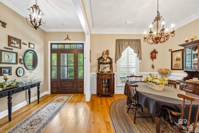 foyer entrance with ornamental molding, an inviting chandelier, and light hardwood / wood-style flooring