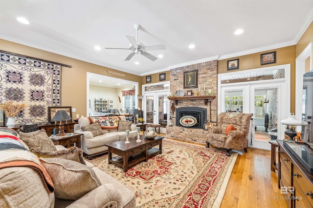 living room featuring ornamental molding, a fireplace, light hardwood / wood-style floors, and french doors