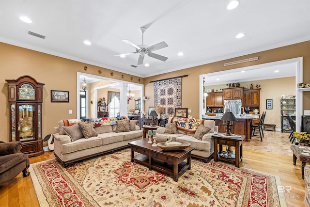 living room featuring ornamental molding, ceiling fan, and light wood-type flooring