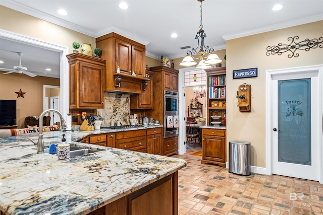 kitchen with pendant lighting, sink, stainless steel appliances, ornamental molding, and decorative backsplash