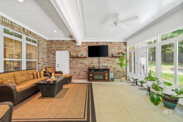 living room with ceiling fan, brick wall, carpet flooring, and a wood stove