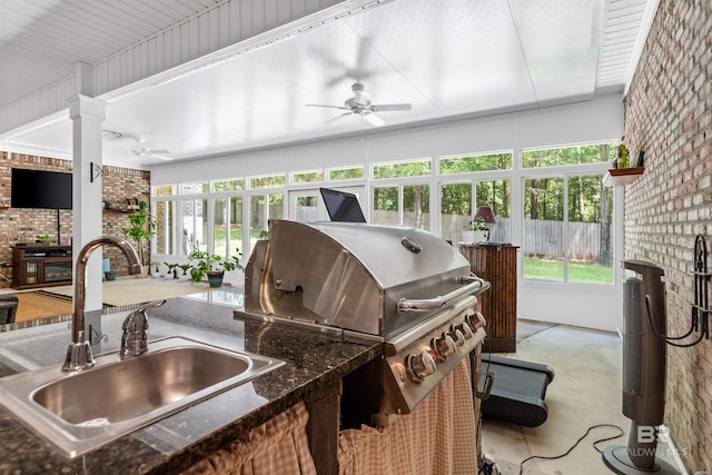 exterior space featuring ceiling fan, a healthy amount of sunlight, brick wall, and sink