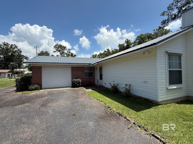 215 W Palm Ave, Foley, AL 36535 - view of front of home with a garage, a metal roof, asphalt driveway, and brick siding