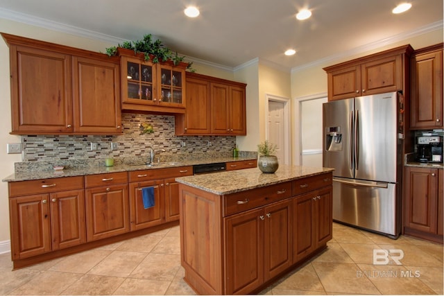 kitchen with light stone counters, a center island, stainless steel refrigerator with ice dispenser, glass insert cabinets, and brown cabinetry