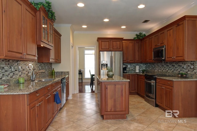 kitchen featuring a kitchen island, glass insert cabinets, appliances with stainless steel finishes, brown cabinets, and light stone counters