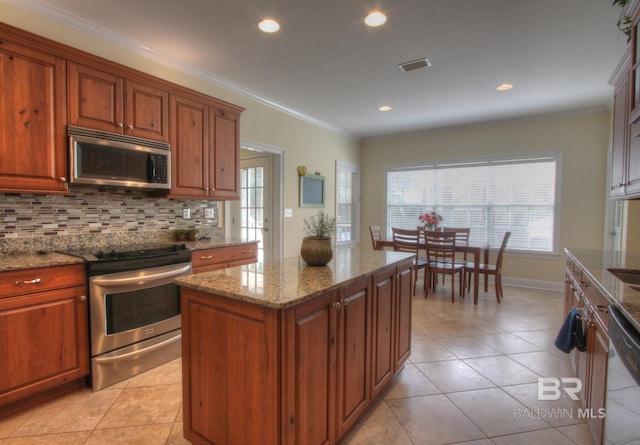 kitchen with light stone counters, crown molding, stainless steel appliances, visible vents, and decorative backsplash