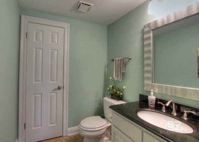 half bathroom featuring toilet, baseboards, visible vents, and vanity